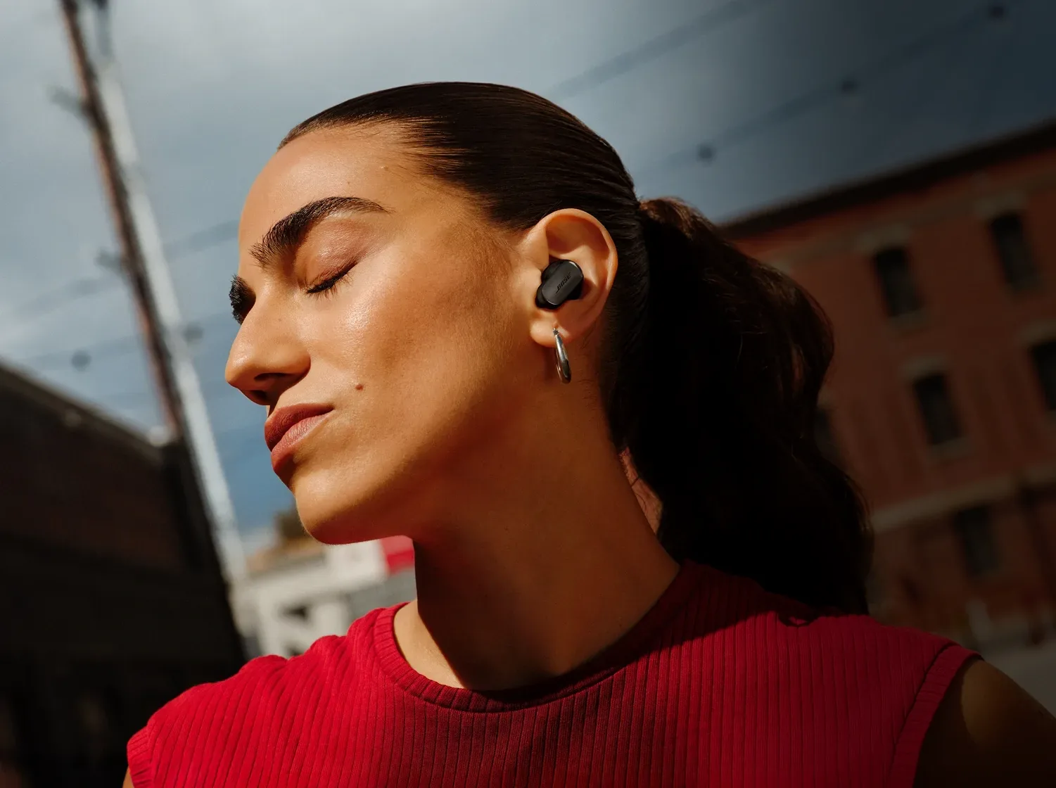 Mujer escuchando música con Bose QuietComfort Ultra Earbuds negros