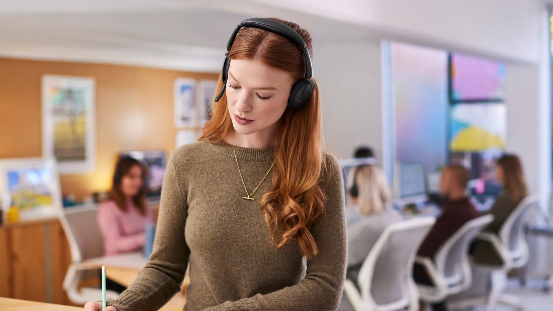 Mujer concentrada en una oficina abierta con el Jabra Evolve2 65 Flex