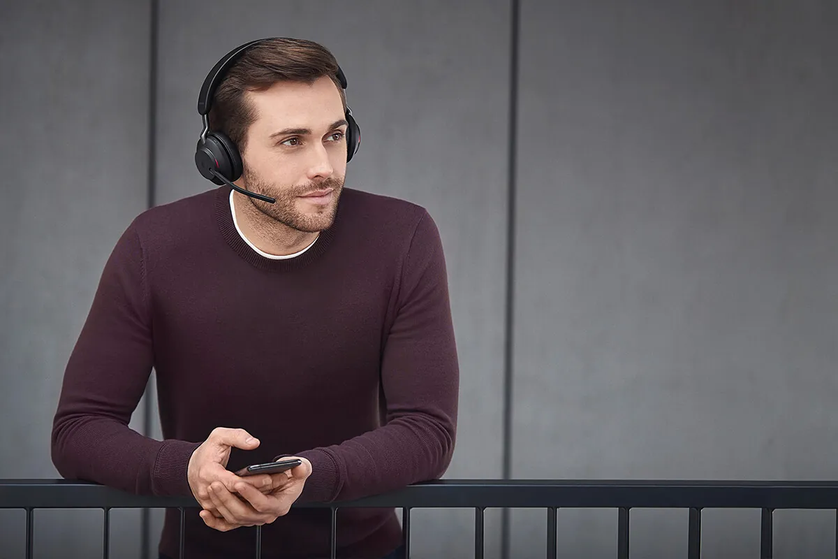 Hombre con el Jabra Evolve2 65 y el celular en la mano