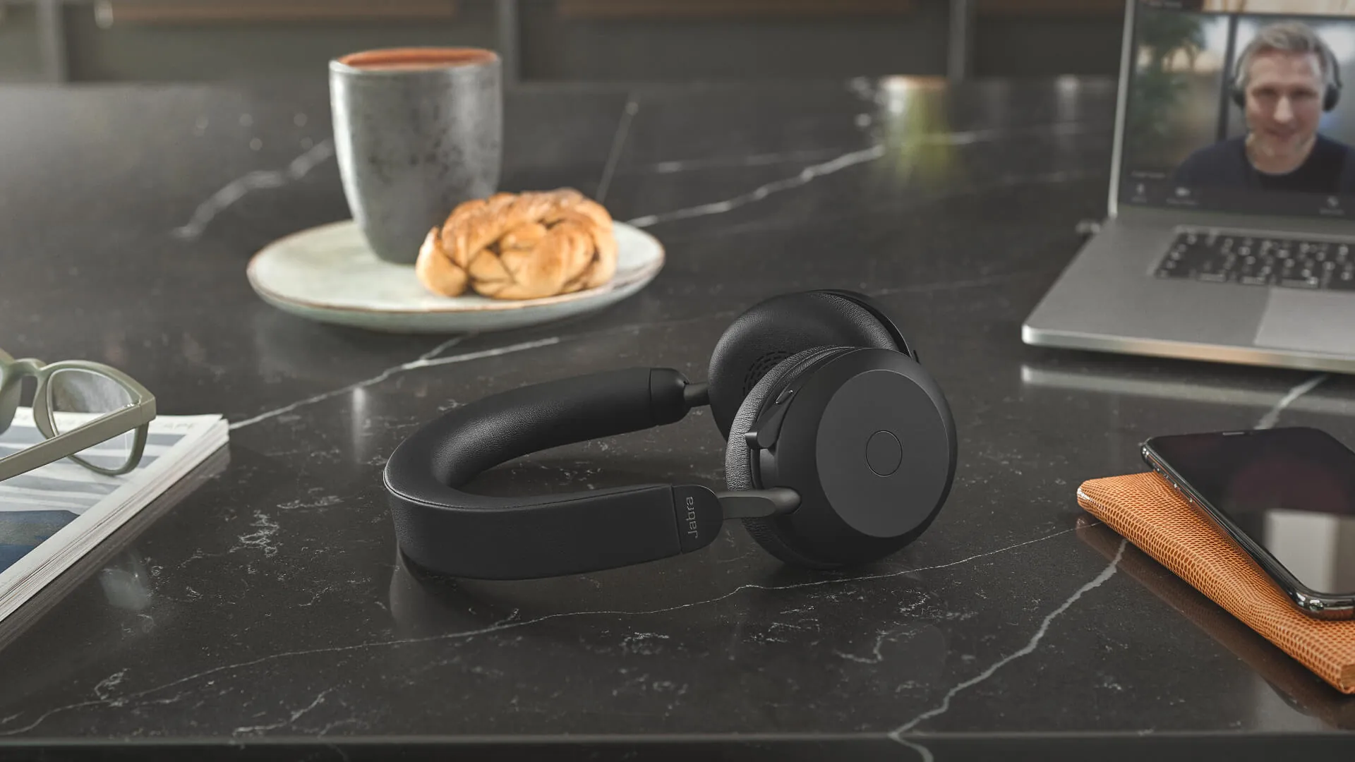 Jabra Evolve2 75 sobre una mesa junto a una notebook y un café