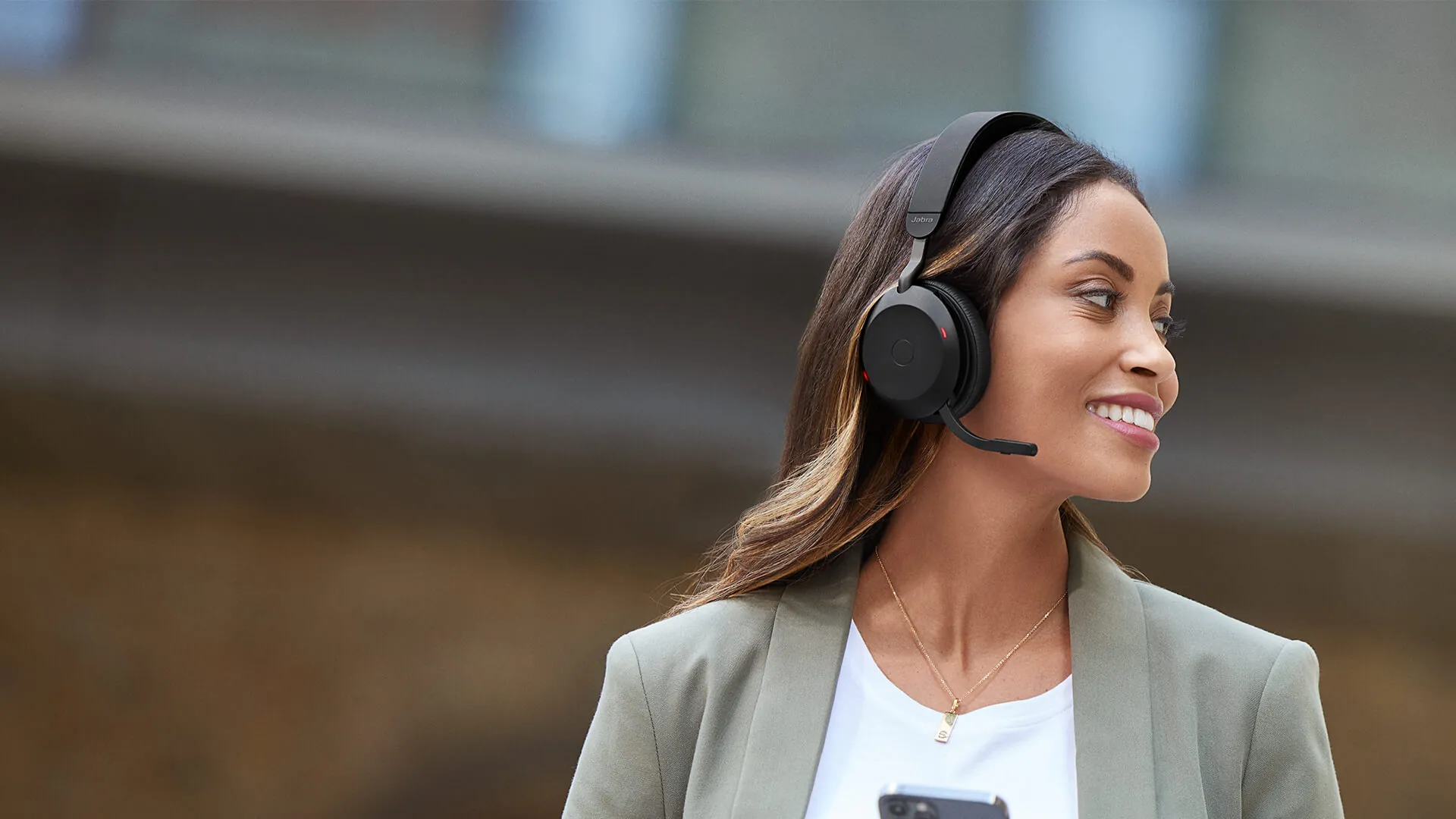 Mujer con los auriculares Jabra Evolve2 75 y el celular en la mano