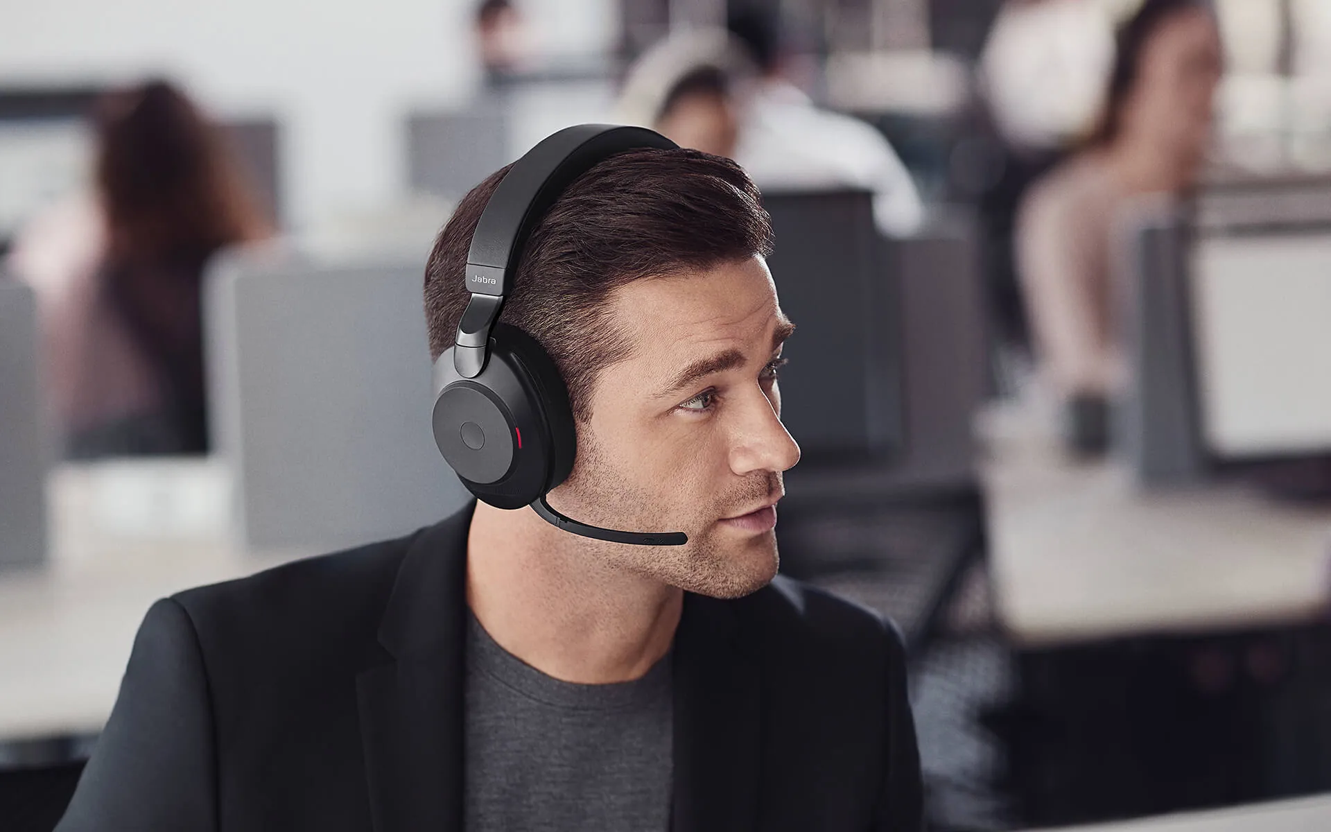 Hombre en una oficina abierta hablando con el Jabra Evolve2 85 y el brazo del micrófono bajado