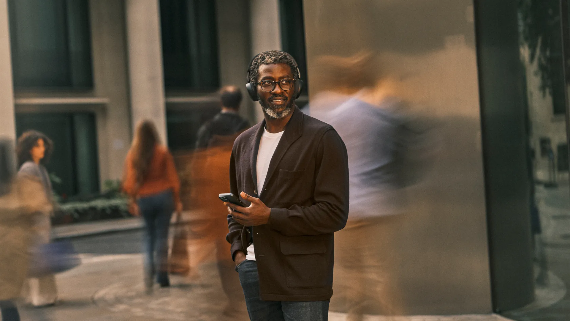 Hombre en la calle con los Jabra Evolve3 75 y el celular en la mano