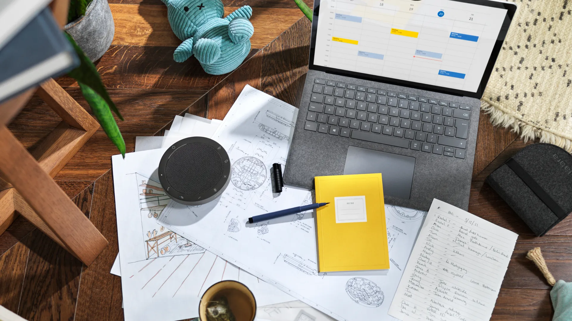 Jabra Speak2 55 sobre un escritorio con planos, una notebook y su bolsa