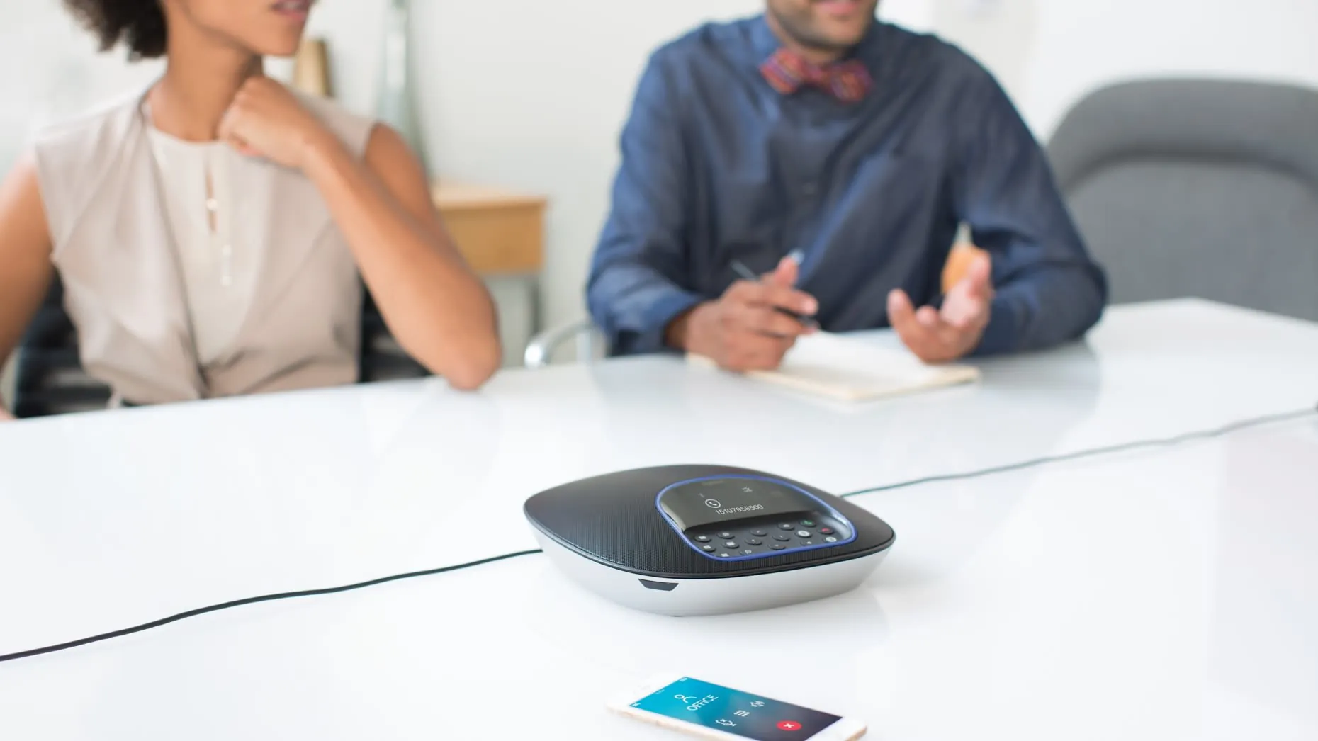 Manos libres del Logitech GROUP con un celular al lado