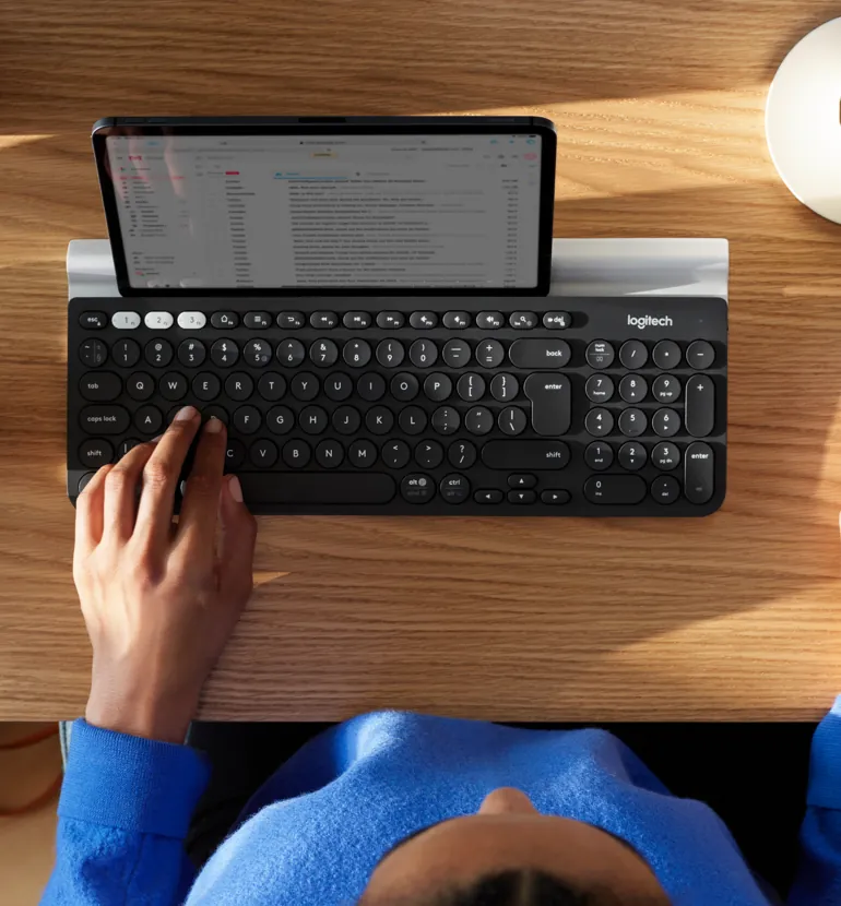 Persona escribiendo en el K780 con una tablet en el soporte