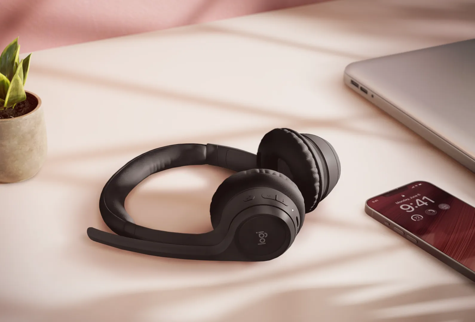 Auriculares Zone 300 sobre el escritorio junto a un celular y una notebook